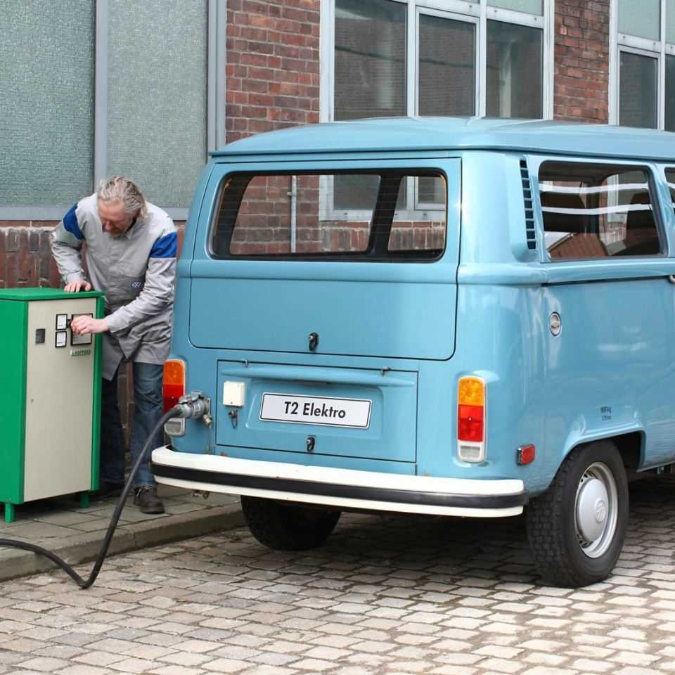 Elektryczny niebieski bus Volkswagen T2 w stacji ładowania elektrycznego